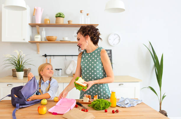 hermosa morena madre y su hija embalaje saludable almuerzo y preparación de la escuela bolsa - healthy eating snack child domestic kitchen fotografías e imágenes de stock