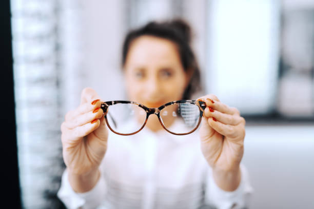안과에서 안경을 들고 있는 여자 안경에 선택적 초점을 저장 합니다. - optics store 뉴스 사진 이미지
