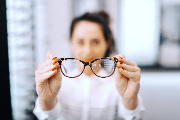 woman holding eyeglasses at ophthalmologist store selective focus on eyeglasses. - patient happiness cheerful optometrist imagens e fotografias de stock