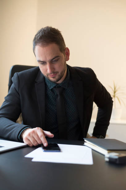 istock businessman in office sending messages with mobile phone smiling 1131848543