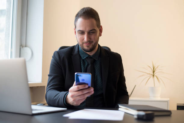 istock businessman in office sending messages with mobile phone smiling 1131848546