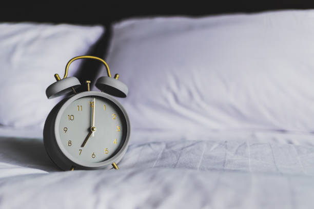 istock Retro gray clock on the white bed in the morning 1131849471
