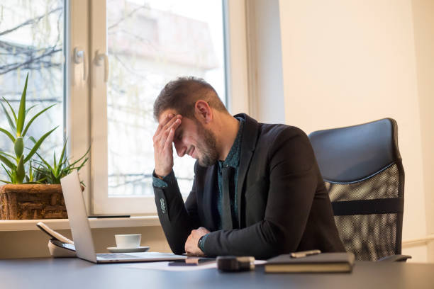 istock businessman working on laptop in office headache 1131850545