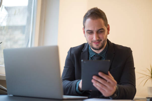 istock businessman working on laptop in office taking notes on tablet 1131850673