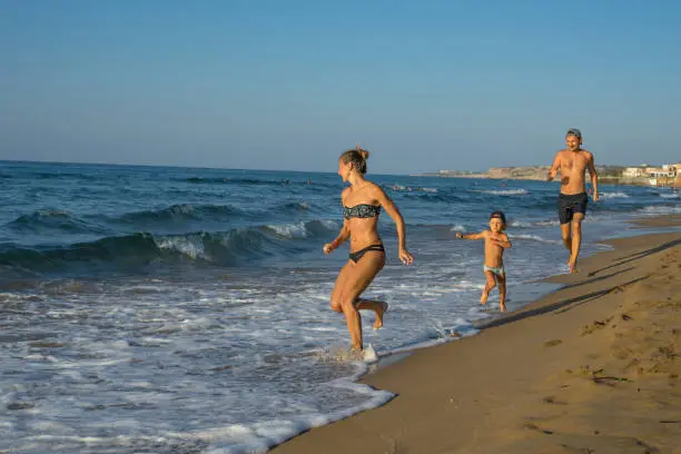 Photo of Happy smiling mother and her son playing and running on the beach. Concept of friendly family. Happy summer days. Greece. Balos Lagoon.