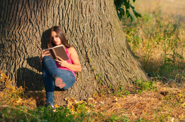 istock Young woman reading book in the nature 1131855044