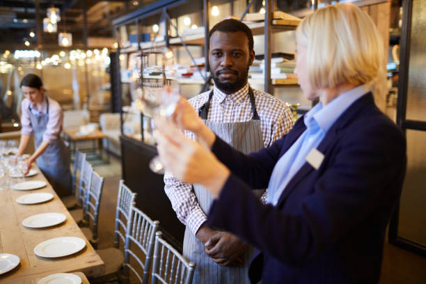 istock Serious banquet manager in formalwear pointing at wineglass while dressing down young black waiter for dirty glass 1131855208