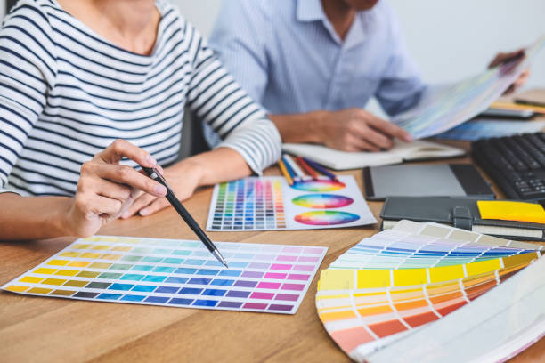 istock Two colleagues creative graphic designer working on color selection and drawing on graphics tablet at workplace, Color swatch samples chart for selection coloring 1131855233