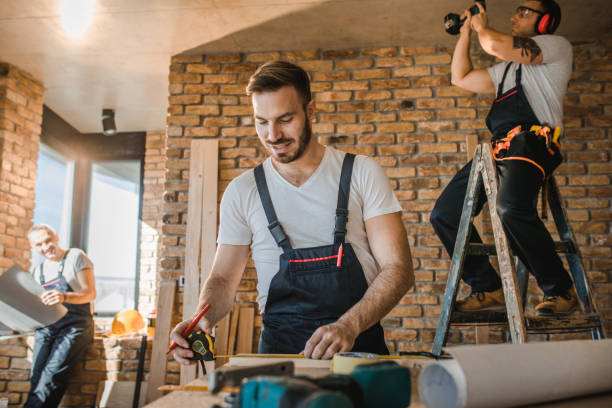 istock Happy manual worker measuring plank while working with his colleagues at construction site. 1131858559