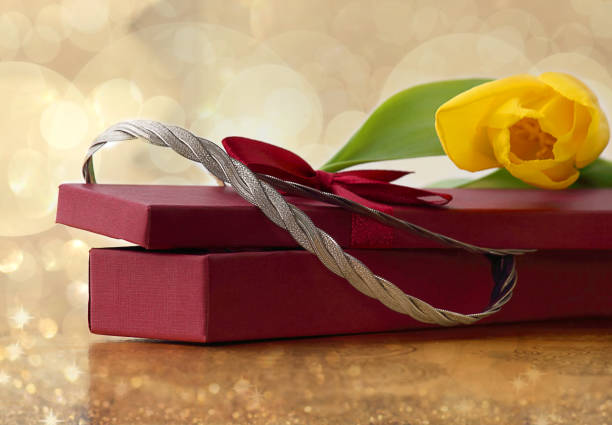 Gift box, silver necklace, flowers of yellow tulips. The concept of a gift to a woman. Selective focus, copy space. Gift box, silver necklace, flowers of yellow tulips. The concept of a gift to a woman. Selective focus, copy space. рождество stock pictures, royalty-free photos & images
