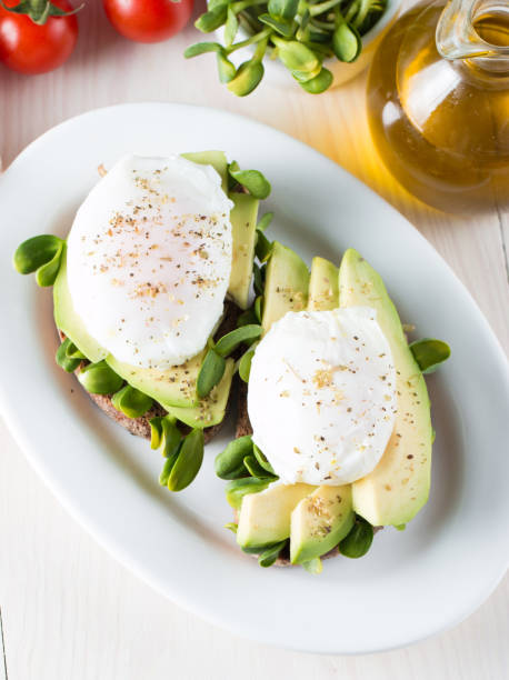 Avocado toast, cherry tomato on wooden background. Breakfast with toast avocado, vegetarian food, healthy diet concept. Healthy sandwich with avocado and poached eggs.