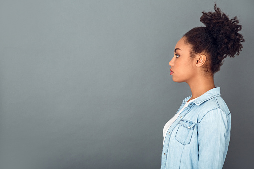 Young african female student isolated on grey wall standing profile looking ahead