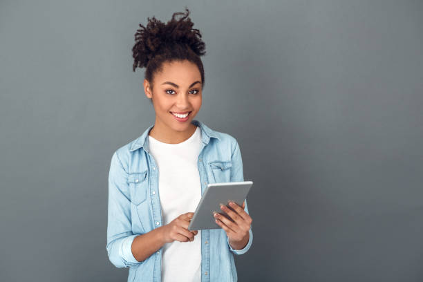 young african woman isolated on grey wall studio casual daily lifestyle holding digital tablet - job joy student computer imagens e fotografias de stock