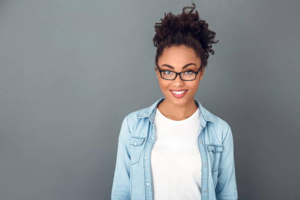 mulher africana nova isolada no sorriso diário ocasional do estudante do estilo de vida do estúdio da parede - african ethnicity standing college student curly hair - fotografias e filmes do acervo