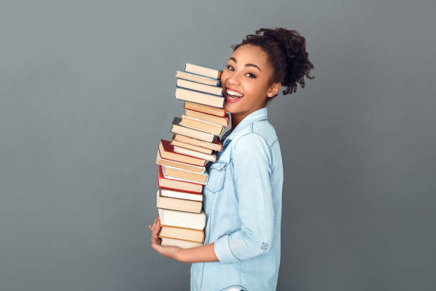 Young african woman isolated on grey wall studio casual daily lifestyle holding books profile stock photo