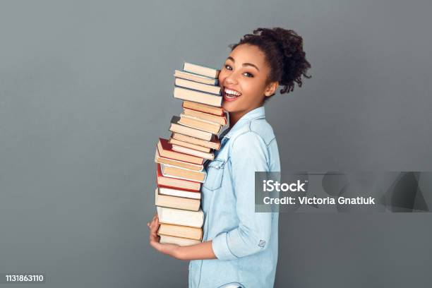Young African Woman Isolated On Grey Wall Studio Casual Daily Lifestyle Holding Books Profile Stock Photo - Download Image Now