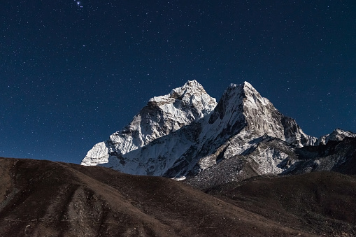 Ama Dablam mountain peak lit up by a bright moonlight on a starry night. Beautiful night mountain landscape under bright moonlight. Stars above himalayan mountain range, Everest Base Camp Trek, Nepal.