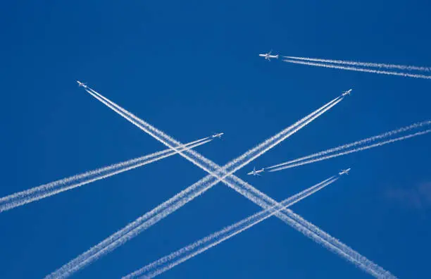 A lot of passenger airplanes on the air, busy air traffic, traveling high season starts concept. White planes against blue sky.  Photomanipulation.