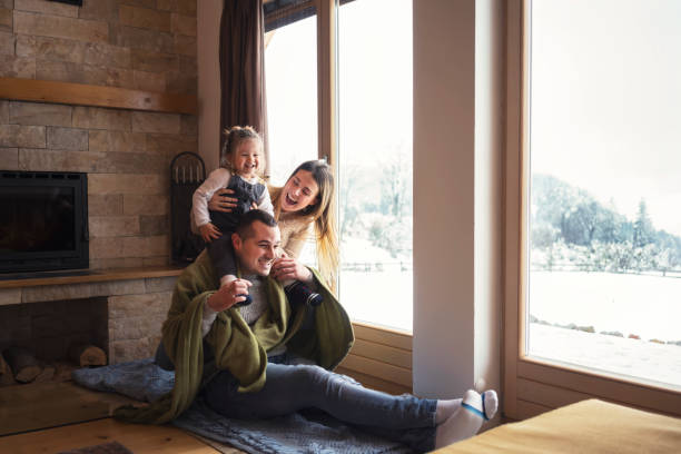 Relaxing by the window Young family on winter vacation, looking through window winter stock pictures, royalty-free photos & images
