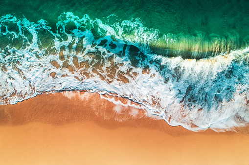 Aerial view of sea waves and sandy beach.