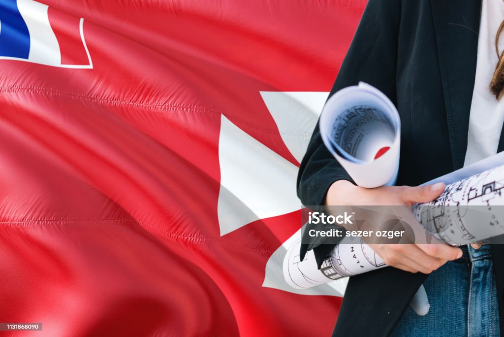 Architect woman holding blueprint against Wallis And Futuna waving flag background. Construction and architecture concept. Adult Stock Photo