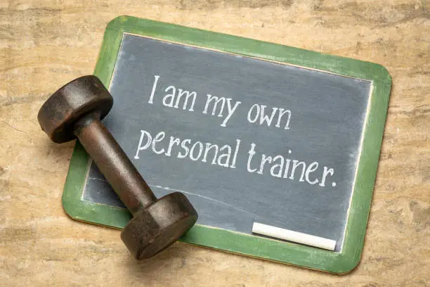 I am my own personal trainer, fitness concept - white chalk text on a slate blackboard with a dumbbell
