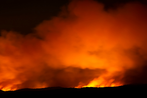 Fire in the mountains at night, background with copy space, full frame horizontal composition