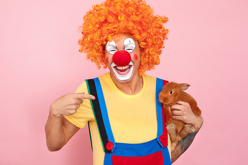  Hombre En Una Peluca Roja Monos Y Maquillaje Sosteniendo Pequeño Conejo Foto de stock y más banco de imágenes de Abril