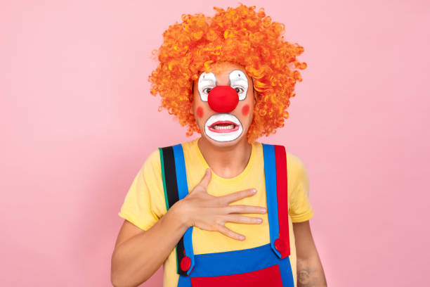 istock Shocked man in a red wig, overalls and makeup looking camera 1131871447