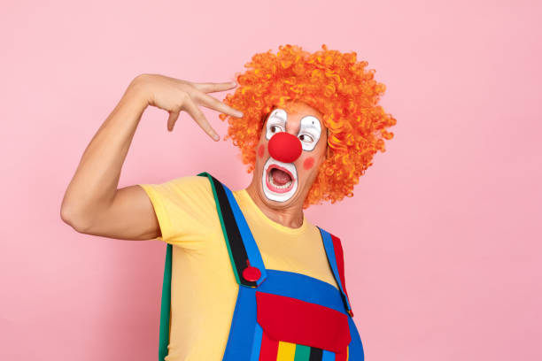 istock Stupid man in a red wig, overalls, makeup scared his hand 1131871469