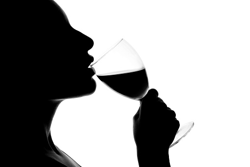 Silhouette of a young woman drinking wine