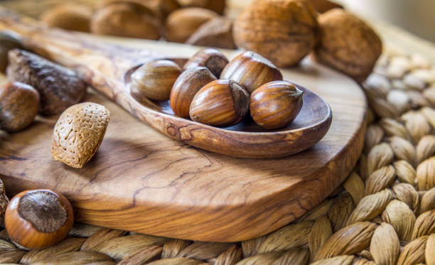 istock Shelled whole hazelnuts on a wooden spoon over a cheese board with mixed nuts in background 1131873055