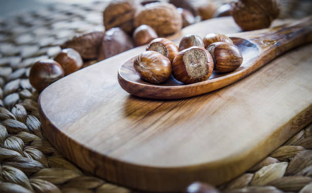 istock Shelled whole hazelnuts on a wooden spoon over a cheese board with mixed nuts in background 1131873059