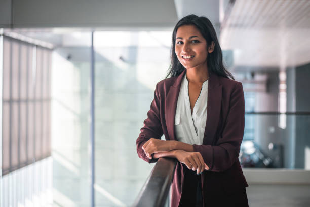 Young indian businesswoman looking at camera and smiling Shot of businesswoman standing and looking at camera. She is smiling and has arms crossed. three quarter length photos stock pictures, royalty-free photos & images
