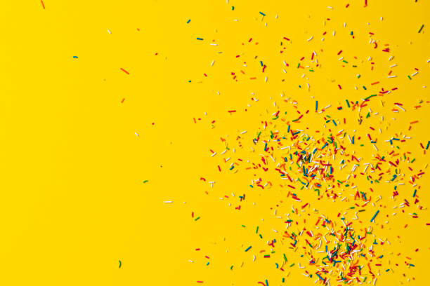 istock Colourful cake sprinkles on yellow background 1131875381