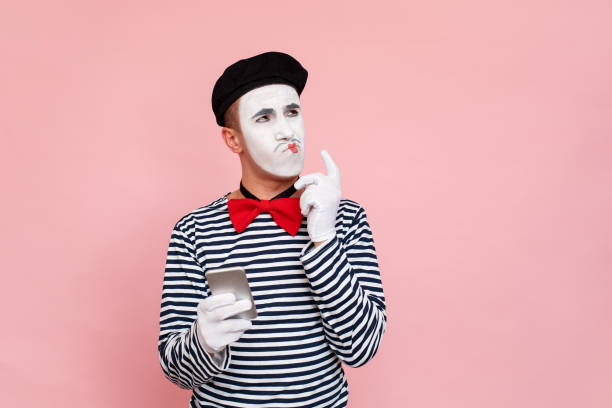 мыслящий мужчина в полосатом свитере, перчатках, держащих смартфон - clown circus telephone humor стоковые фото и изображения
