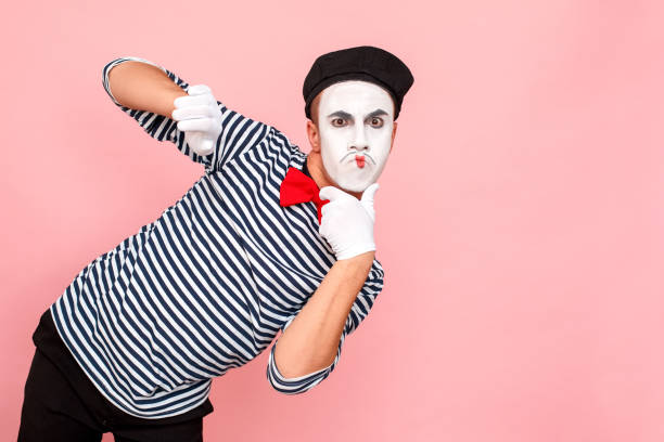 Puzzled man in striped sweater, white gloves with perplex face. Clown, artist , mime. Studio shot, pink background