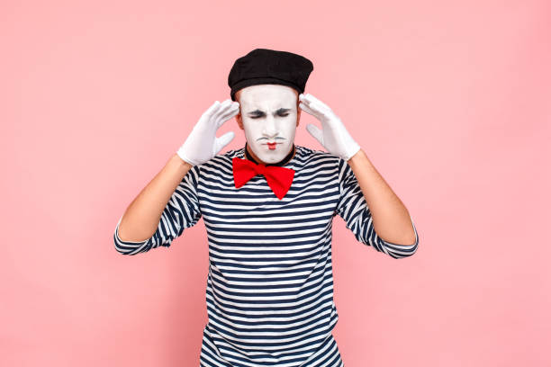 Actor have headache, migraine. Holding hands head. Clown, artist , mime Studio shot pink background