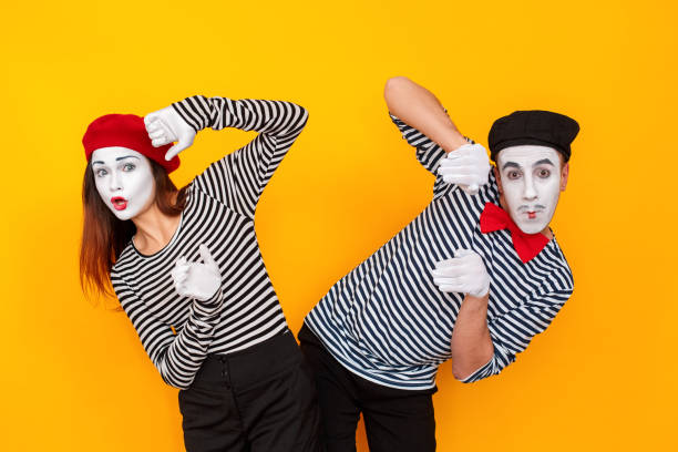 Portrait of shocked couple looking at camera with wondered Portrait of shocked couple looking at camera with wondered. Show time. Indoor shot, yellow background mime artist stock pictures, royalty-free photos & images