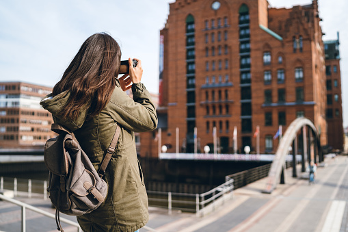 Young tourist woman is photographing surroundings in Hafen City, Hamburg, Germany