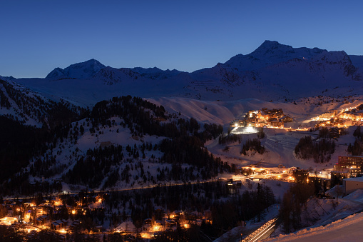 La Plagne ski resort in French Savoy Alps at twilight in winter. View of snow covered mountains and buildings just before sunrise