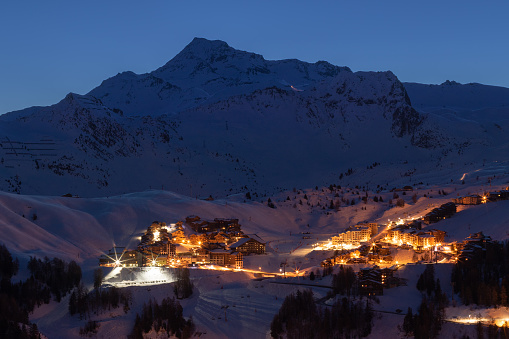 La Plagne ski resort in French Savoy Alps at twilight in winter. View of snow covered mountains and buildings just before sunrise