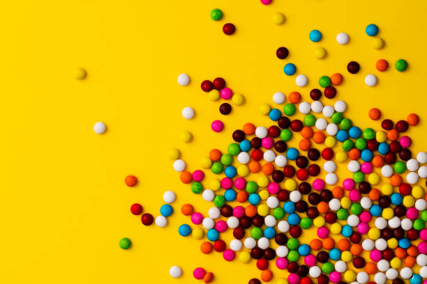 Colurful chocolate beans on yellow background.