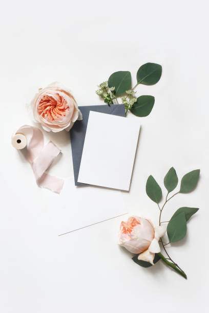 boda femenina, escena de maqueta de cumpleaños. tarjetas de felicitación de papel en blanco, sobre, cinta de seda, hojas de eucalipto y blush rosado rosas flores inglesas. fondo de la mesa blanca. lay plano, vista superior, vertical. - fruit blossom fotos fotografías e imágenes de stock