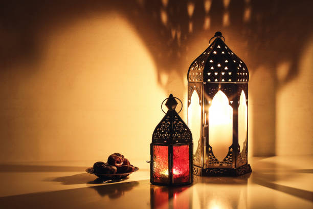 istock Ornamental Arabic lanterns with burning candles glowing at night. Plate with date fruit on the table. Festive greeting card, invitation for Muslim holy month Ramadan Kareem. Iftar dinner background. 1131880052