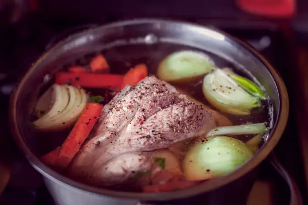 preparing a soup with a big part of meat, onions and carrots in a saucepan