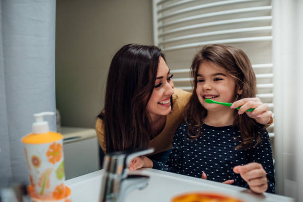 mother and daughter brushing teeth - human teeth child smiling family imagens e fotografias de stock