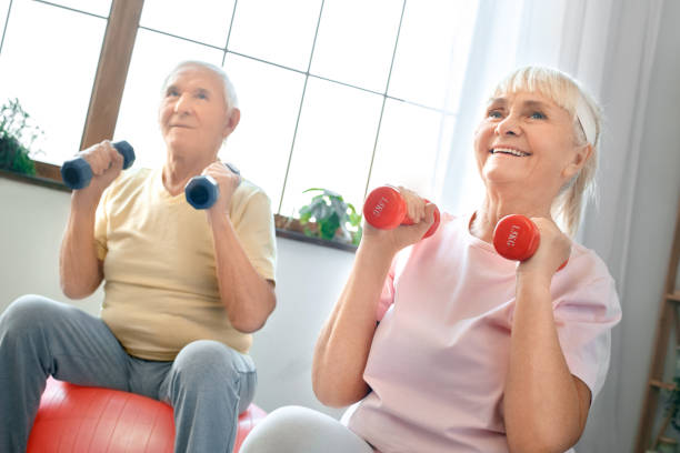 istock Senior couple exercise together at home doing aerobics holding dubbells 1131883024