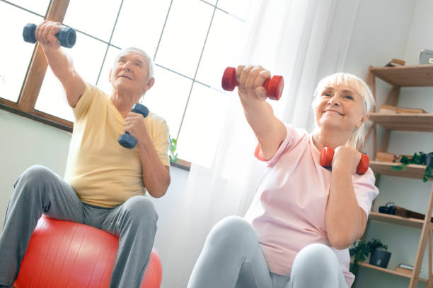 istock Senior couple exercise together at home doing aerobics with dubbells in front 1131883034