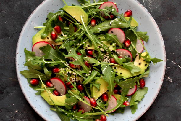 istock Ingedient for making salad on dark background. Vegetable salad in plate, avocado, arugula, pomegranate, radish and sesame. 1131883568